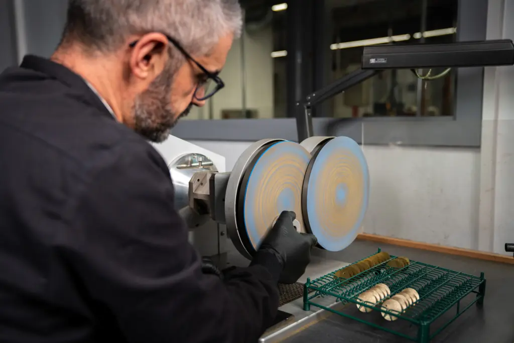 Artisan Montremo polissant des cadrans de montre sur machine de finition dans la manufacture de La Chaux-de-Fonds